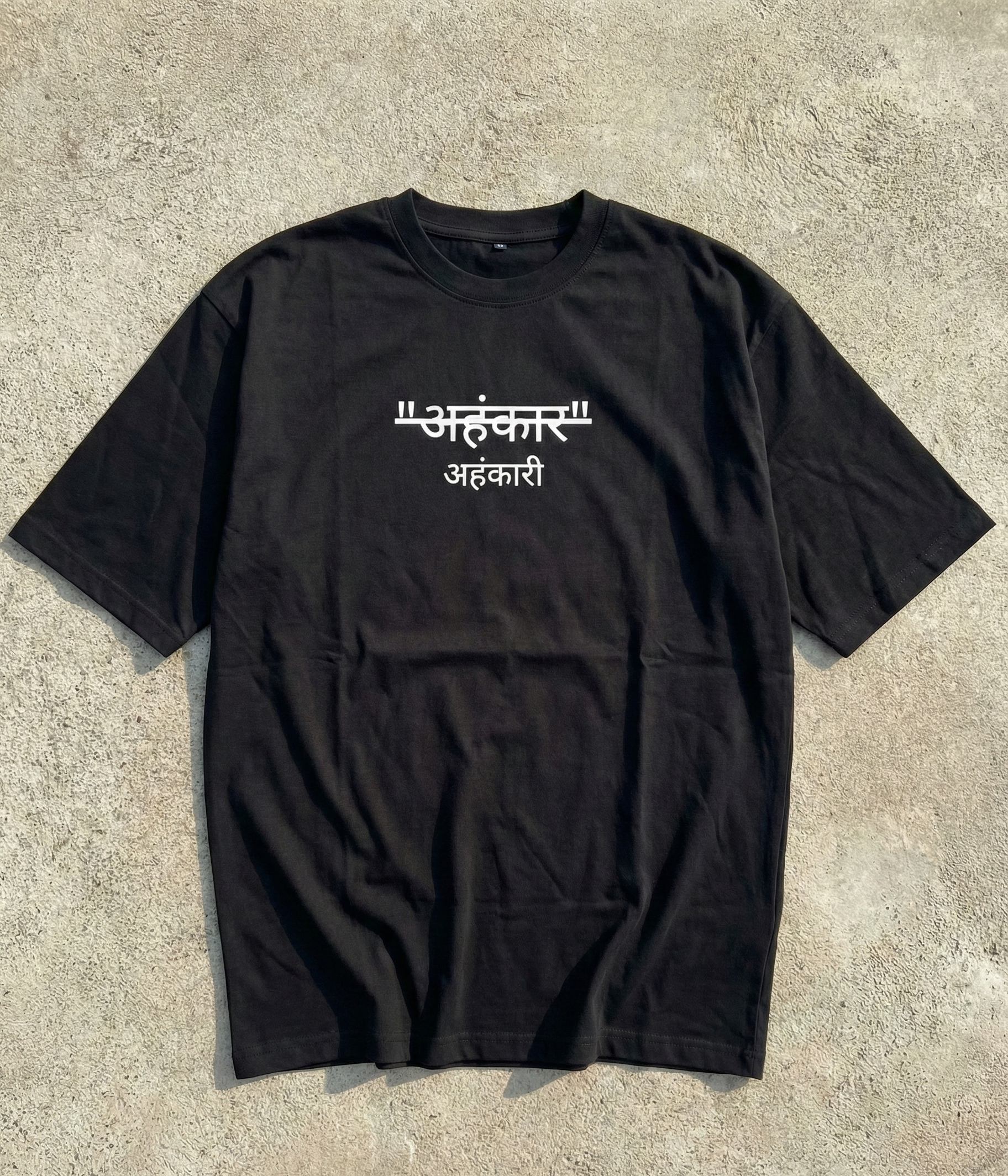 Black t-shirt with white text on a concrete surface